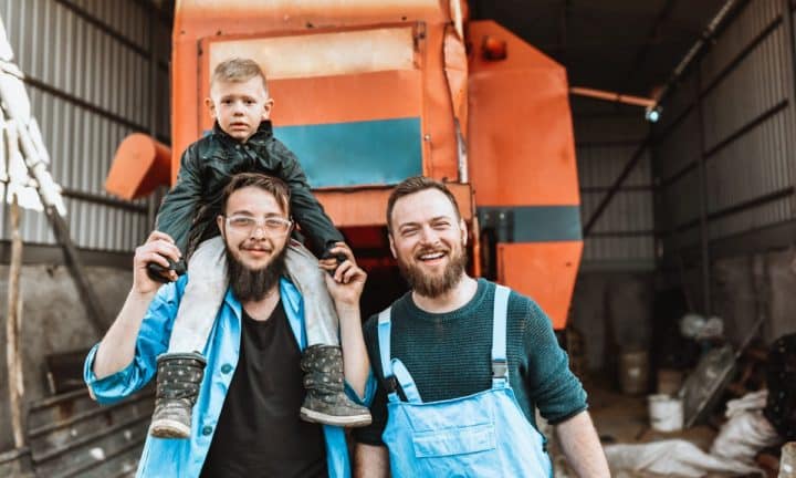 Two farmers standing with their child