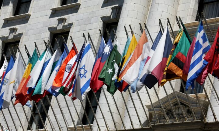 Flags of many nations hang outside of a UN headquarters building.